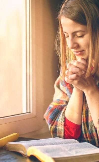 woman praying with open Bible